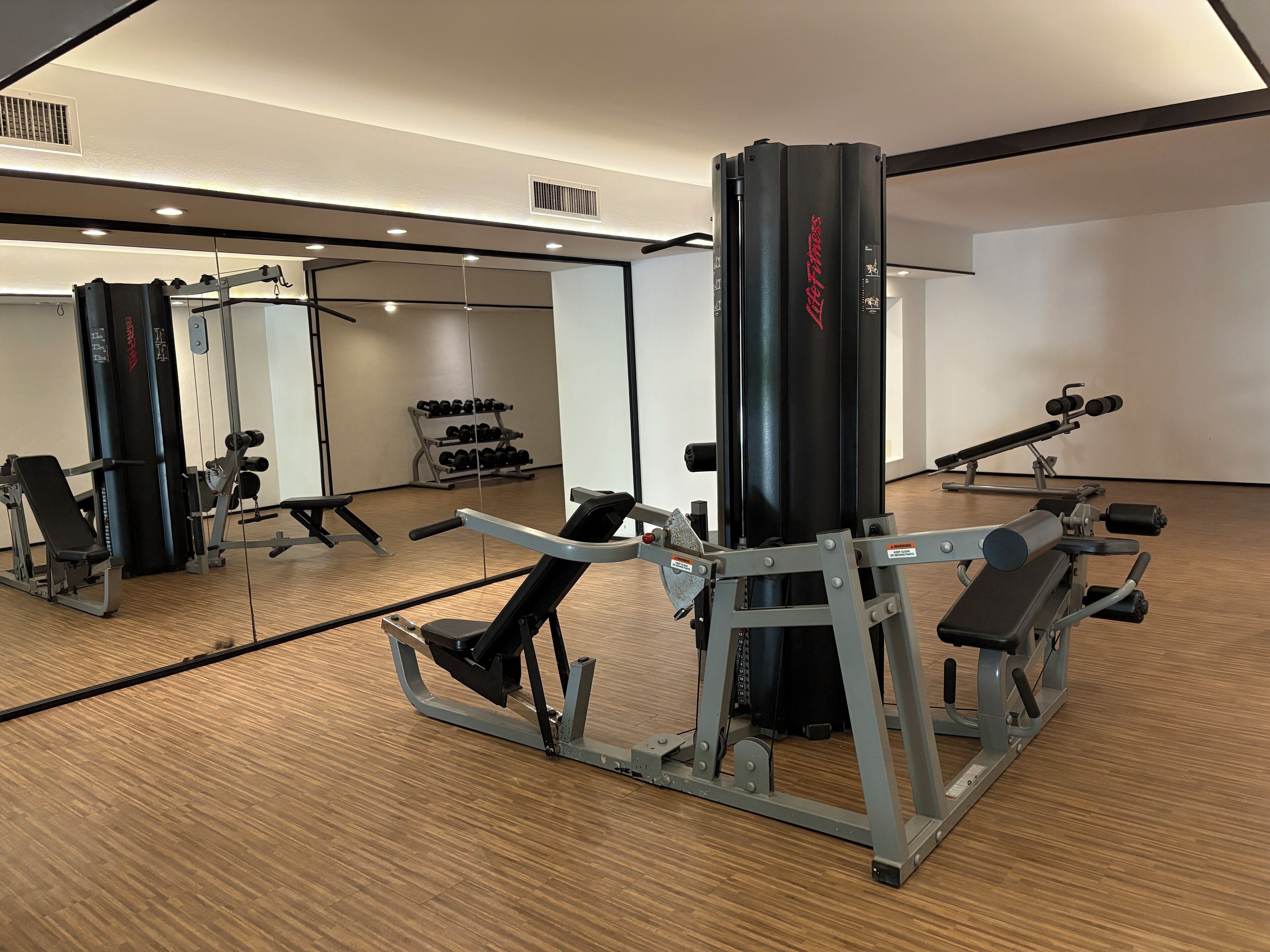 A gym with various exercise equipment, including a bench press, a squat rack, and dumbbells.