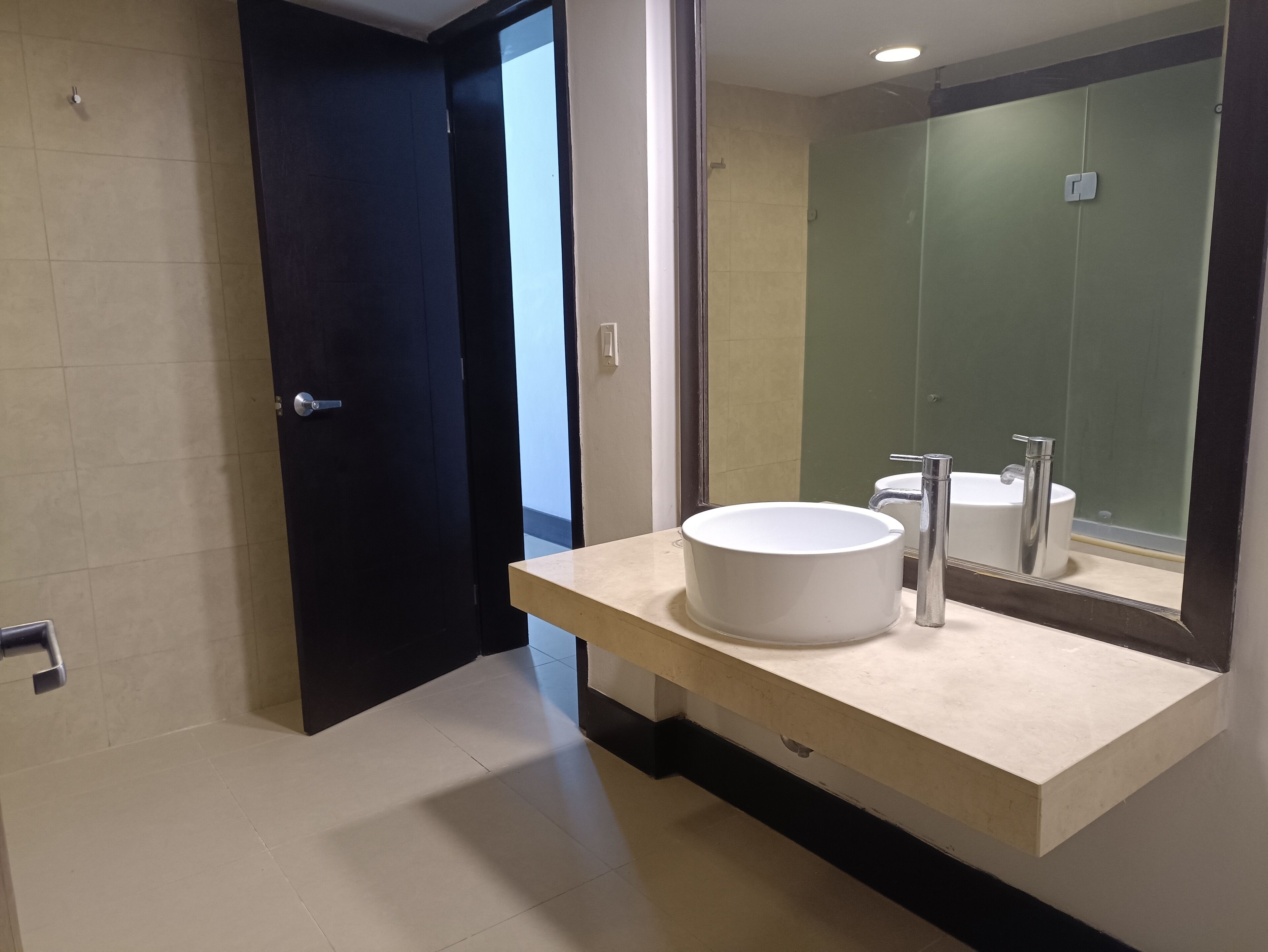 A modern bathroom with a large mirror, a white sink, and a shower area.