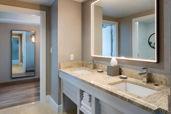 A modern bathroom with two sinks, a large mirror, and a towel rack.