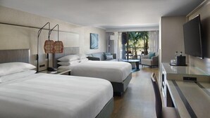 A hotel room with two beds, a desk, a chair, a TV, and a balcony with a view.