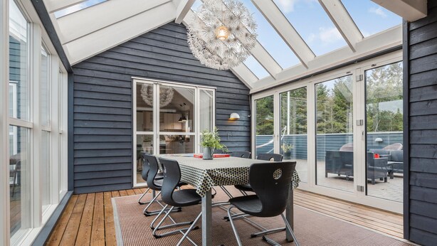 Ett modernt matområde med ett bord och stolar, en hängande lampa och stora fönster.