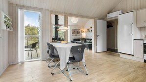 Ett modernt kök med matplats, trägolv och ett stort fönster med utsikt över trädgården.