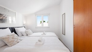 Une chambre avec deux lits, une armoire en bois, une fenêtre donnant sur un beau paysage et un tableau encadré au mur.