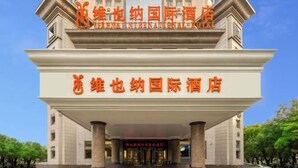 Een hotelentree met een groot bord in Chinese karakters, een statig entree met kolommen en een heldere lucht op de achtergrond.