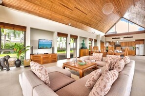 A spacious living area with a large sofa, wooden coffee table, and a television. - Baan Grand Vista - Panoramic Sea View (Koh Samui)