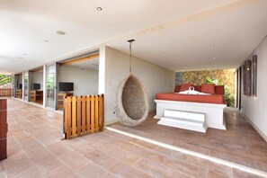 A spacious room with a large bed, a hanging chair, and a wooden partition. - Baan Grand Vista - Panoramic Sea View (Koh Samui)