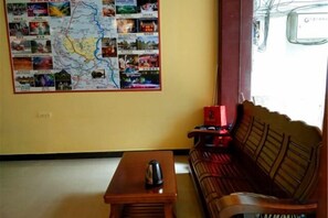 A room with a map on the wall, a wooden table with a cup, and a sofa. - Huaxia Boutique Inn (Yangshuo West Street Branch) (Yangshuo)