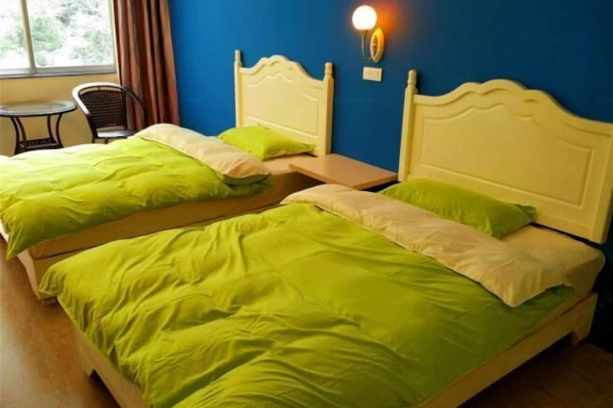 A room with two beds, a small table, and a chair.