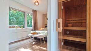 Een slaapkamer met een bed, nachtkastje en een raam met gordijnen.