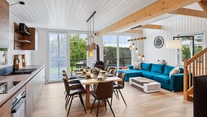 A spacious living area with a dining table, blue sofa, and a kitchen with wooden cabinets and a modern stove. - Stunning home in Wandlitz OT Zerpenschl with house a panoramic view (Wandlitz OT Zerpenschl)