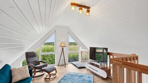 A spacious attic room with a large window, a television, a rocking chair, and a blue rug. - Stunning home in Wandlitz OT Zerpenschl with house a panoramic view (Wandlitz OT Zerpenschl)