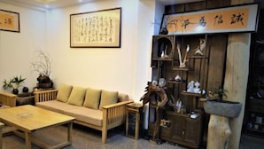 A cozy living room with a sofa, a wooden coffee table, and a bookshelf filled with decorative items. - Benyuan Hostel (Wuyishan)