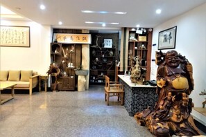 A traditional interior with a sofa, wooden furniture, and a statue. - Benyuan Hostel (Wuyishan)