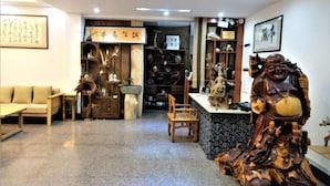 A traditional interior with a wooden sofa, a carved wooden statue, and shelves with various items. - Benyuan Hostel (Wuyishan)