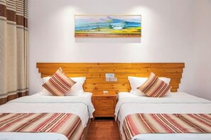 A hotel room with two beds, a wooden headboard, and a painting on the wall. - Benyuan Hostel (Wuyishan)