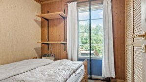 A bedroom with a bed, a wooden shelf, a window with curtains, and a view of greenery outside. - Amazing home in Sydals with WiFi (Sydals)