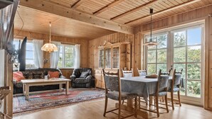 A cozy cabin interior with a wooden dining table, chairs, a sofa, and a fireplace. - Amazing home in Sydals with WiFi (Sydals)