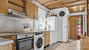 A compact kitchen with wooden cabinets, a built-in oven, a washing machine, and a coffee maker. - Amazing home in Sydals with WiFi (Sydals)