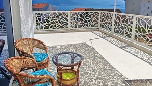 Een balkon met rieten meubilair, een patroon vloer en een uitzicht op verre bergen.