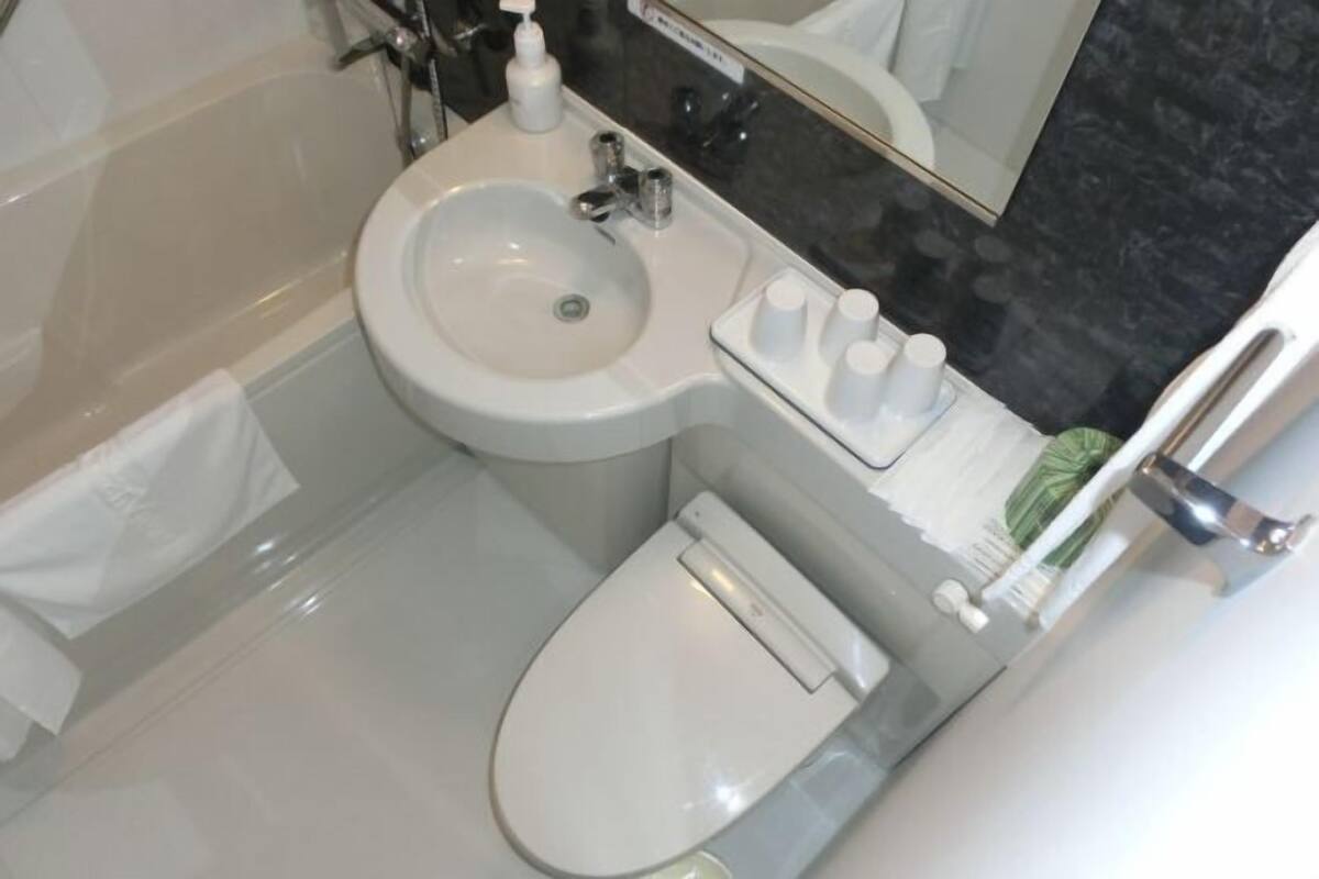 A bathroom with a toilet, sink, and mirror.
