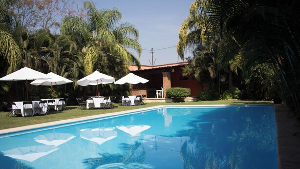 A swimming pool with white umbrellas and chairs, surrounded by palm trees. - Quinta Olivos!!, UN Espacio Para TU Descanso...!! (Mor.)