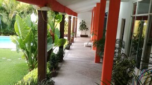 A covered corridor with red pillars, potted plants, and a view of a swimming pool. - Quinta Olivos!!, UN Espacio Para TU Descanso...!! (Mor.)