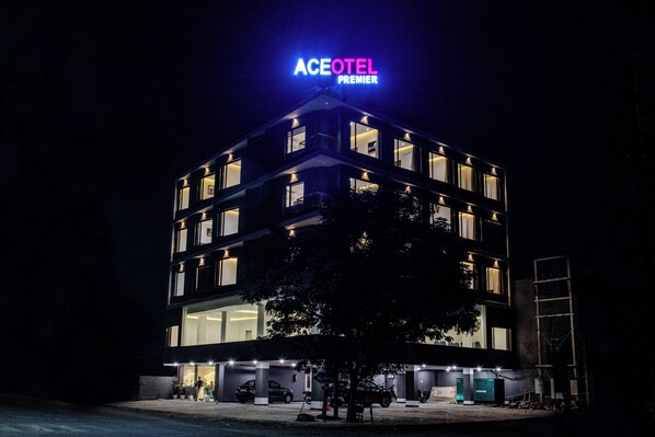 A multi-story hotel with a prominent neon sign, multiple balconies, and a parking area. - Aceotel Premier Vijay Nagar (Indore)