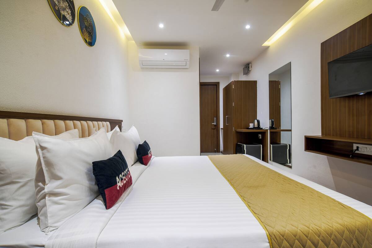 Une chambre d’hôtel avec un grand lit, un téléviseur à écran plat, une armoire et un bureau avec une chaise.