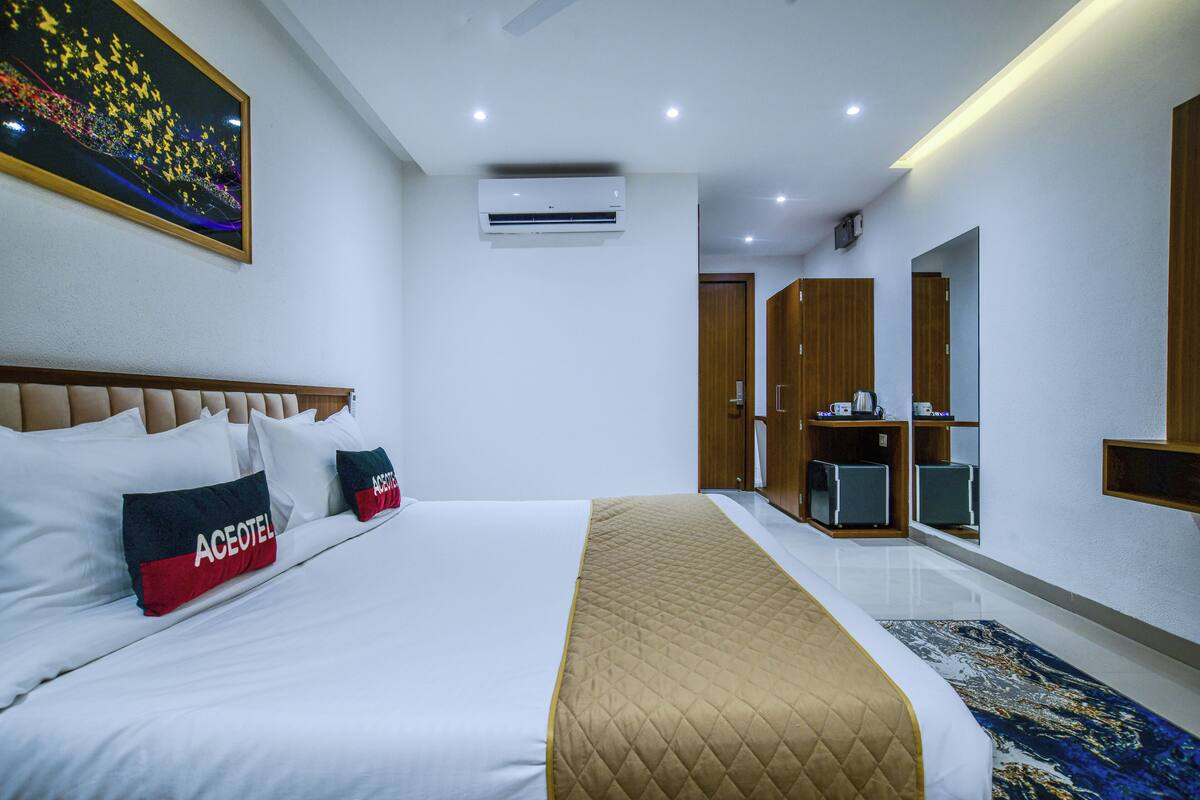 Une chambre d’hôtel avec un grand lit, un appareil de climatisation, une armoire et un miroir.