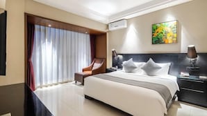 A hotel room with a large bed, a chair, a desk, and a painting on the wall. - Haikou Manyue Hot Spring Hotel (Hainan University Branch) (Haikou)