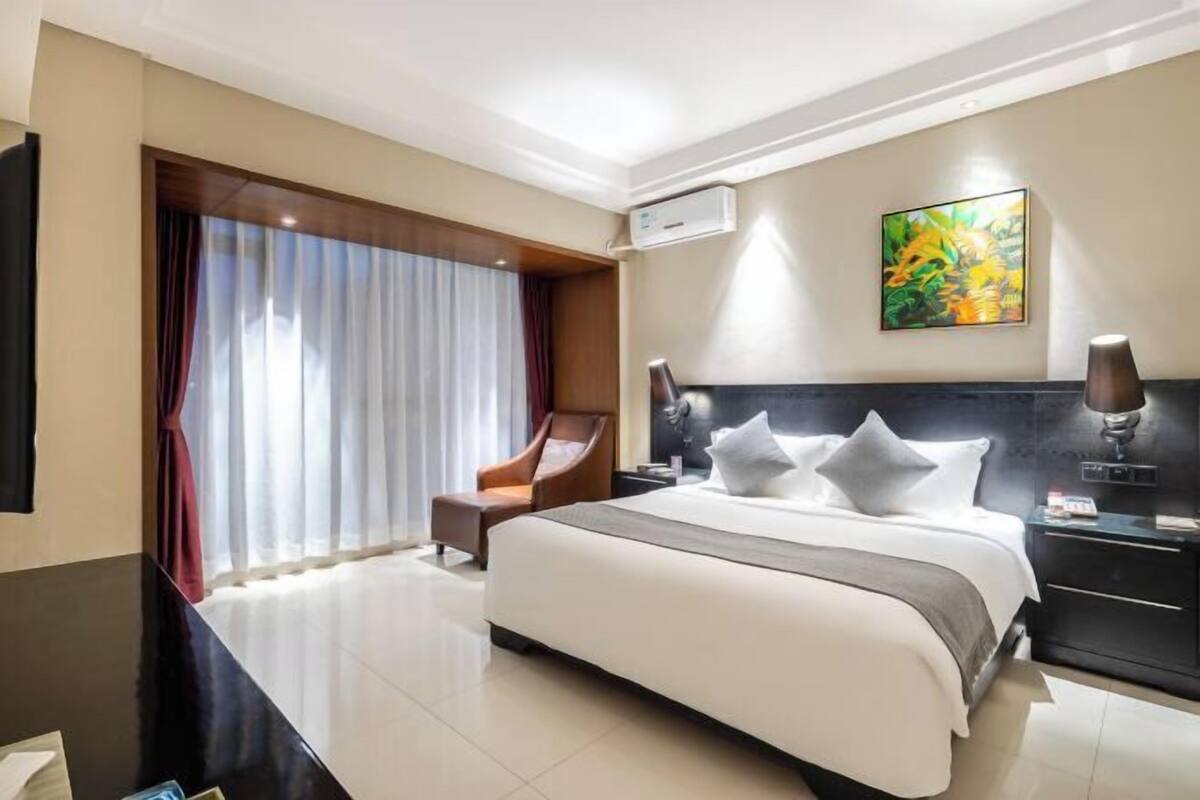 Une chambre d’hôtel avec un grand lit, une chaise, un bureau et un tableau au mur.