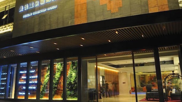 A hotel exterior with a modern design, large windows, and a sign indicating it is a hotel collection. - Haikou Manyue Hot Spring Hotel (Hainan University Branch) (Haikou)