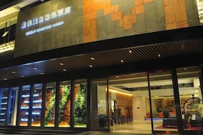 A hotel exterior with a modern design, large windows, and a sign indicating it is a hotel collection. - Haikou Manyue Hot Spring Hotel (Hainan University Branch) (Haikou)