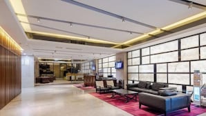 A modern lobby with a seating area, a reception desk, and a large window with a view. - Haikou Manyue Hot Spring Hotel (Hainan University Branch) (Haikou)