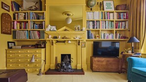 A living room with a fireplace, a television, and bookshelves filled with books. - Charming East London Apartment (London)