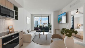 Un appartement moderne doté d’une cuisine, d’un espace de vie et d’un balcon offrant une vue sur la ville.