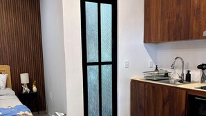 Eine kleine Küche mit einem Holzkorpus, einer Spüle und einem Fenster mit Milchglas.