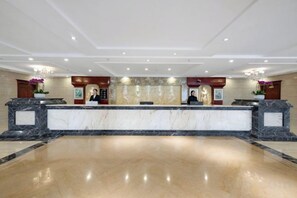 A hotel reception area with marble counters, a reception desk, and a large open space. - Huquan Bund Hotel (Mile)