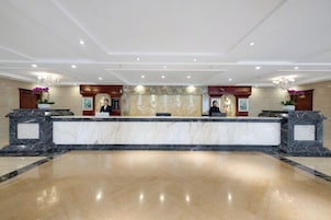 A hotel reception area with marble counters, a reception desk, and a large open space.