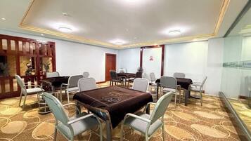 Uma sala de conferências com uma mesa grande, cadeiras e um piano.
