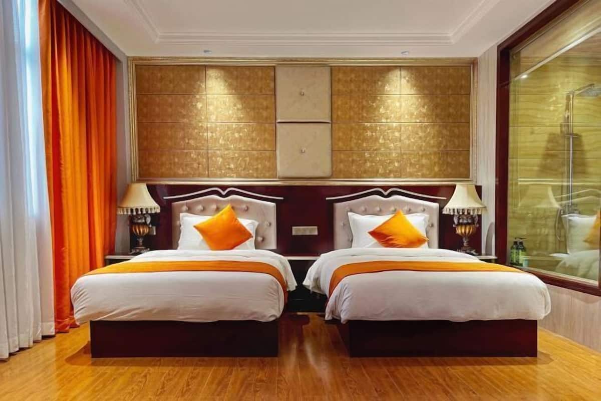 A hotel room with two beds, a large window, and a decorative wall panel.