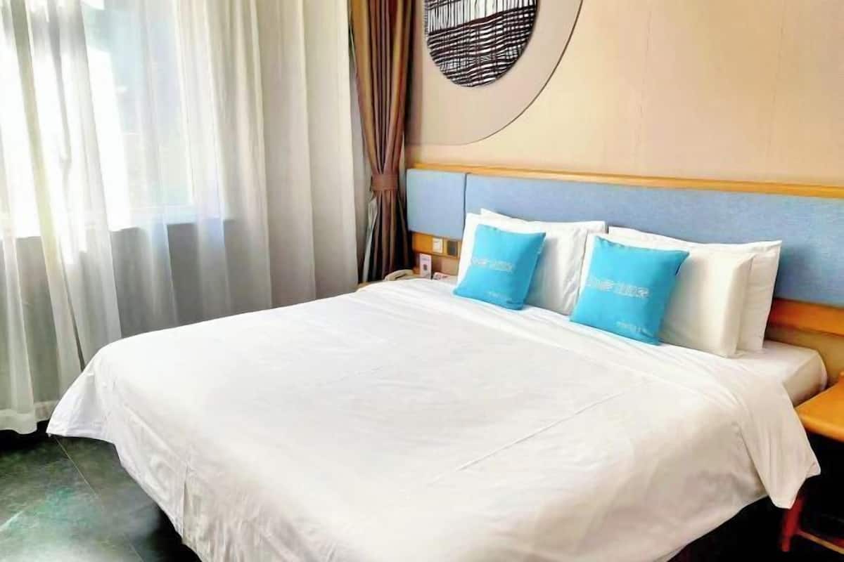 Une chambre d’hôtel avec un grand lit, du linge de lit blanc et des oreillers bleus.