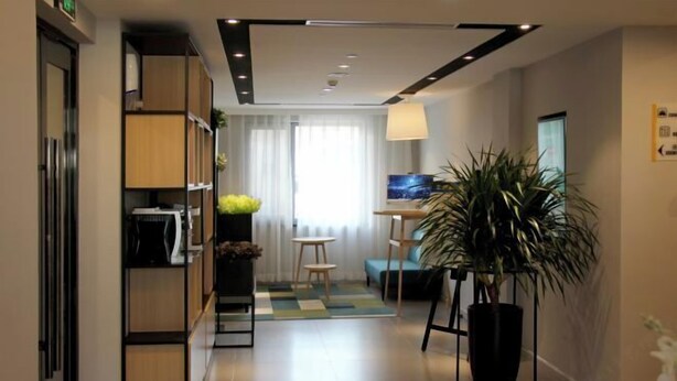 A modern hotel lobby with a reception desk, seating area, and a large potted plant. - Homeinn Hotel (Beijing Sihui Baiziwan Subway Station) (Beijing)