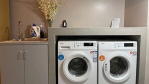 A laundry area with two front-loading washing machines, a sink, and a vase with flowers. - Homeinn Hotel (Beijing Sihui Baiziwan Subway Station) (Beijing)
