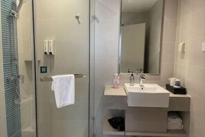 A bathroom with a glass shower enclosure, a white sink, a mirror, and a towel rack. - Homeinn Hotel (Beijing Sihui Baiziwan Subway Station) (Beijing)