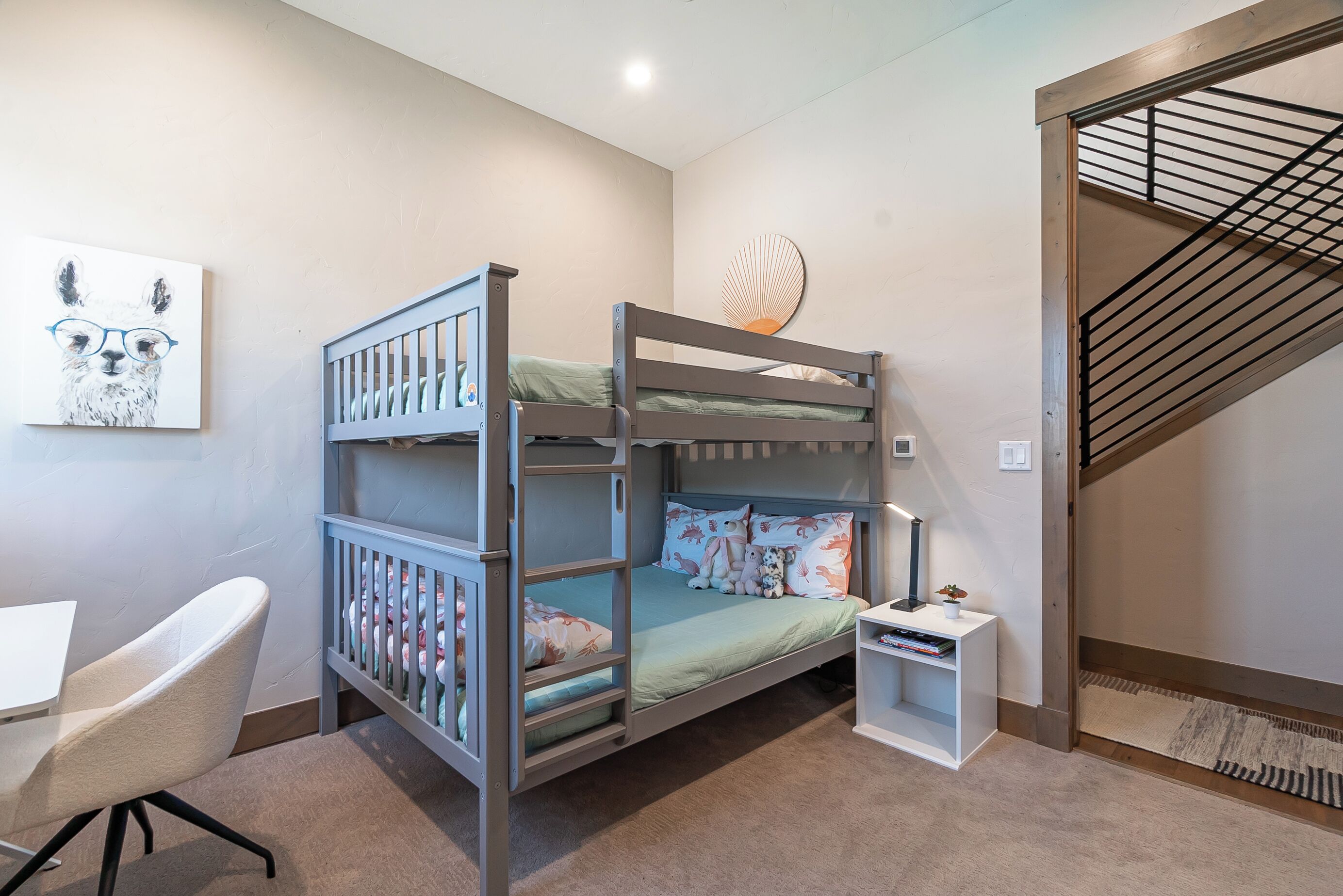 A bunk bed with a desk and chair, a small shelf, and a wall-mounted shelf.