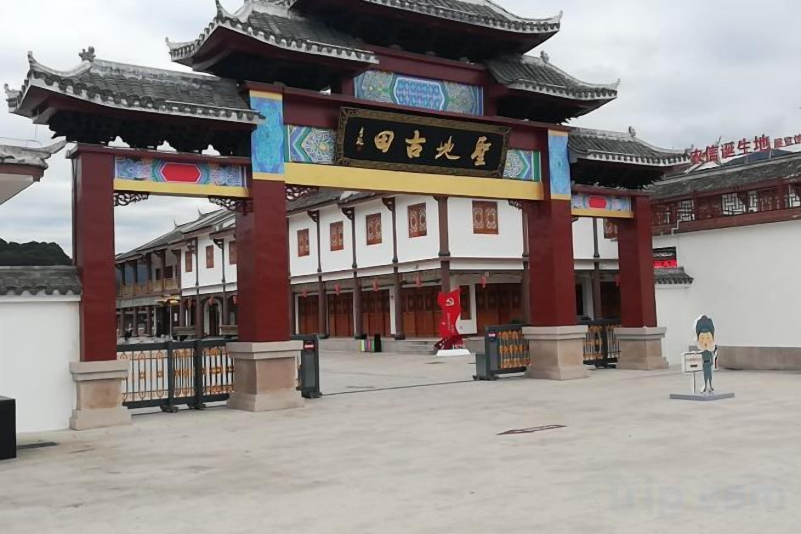 A traditional Chinese gate with a sign, leading to a building with multiple doors.