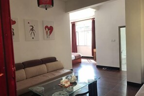 Una sala de estar con un sofá, una mesa de centro de vidrio y obras de arte en la pared.