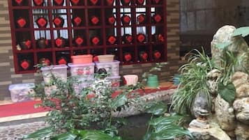 A room with a tiled floor, a red carpet, a window with red decorations, and a small water feature.