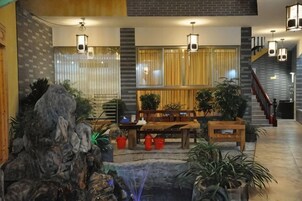Un hall con escalera, zona de estar y plantas en macetas.